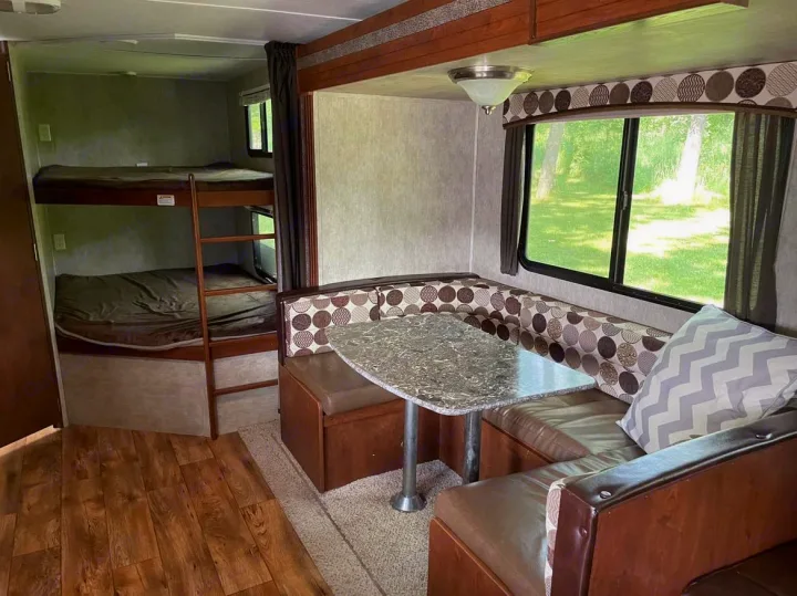 RV rental interior: cozy bunk beds to the left, and a comfortable U-shaped dinette with a table to the right.. Keystone RV Passport Ultra Lite 2015