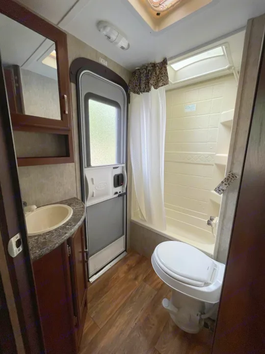 RV rental: Compact bathroom with sink, toilet, shower/tub, and exit door. Functional for your travels.. Keystone RV Passport Ultra Lite 2015
