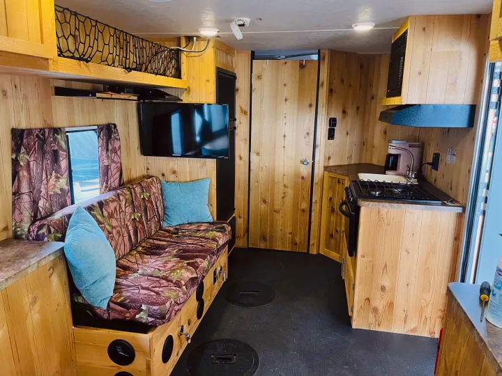 RV rental interior featuring a wood-paneled living area, kitchen, and unique floor hatches for ice fishing.. Forest River Cherokee Grey Wolf 2015