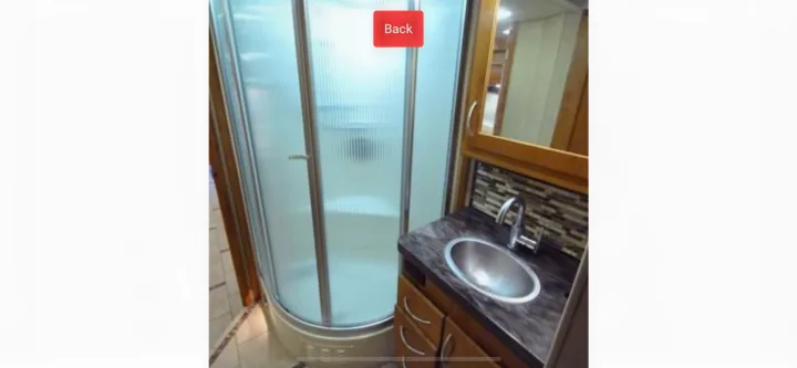 RV rental bathroom: compact corner shower with frosted door, vanity with oval sink & mirrored cabinet.. Monaco Vesta 2012