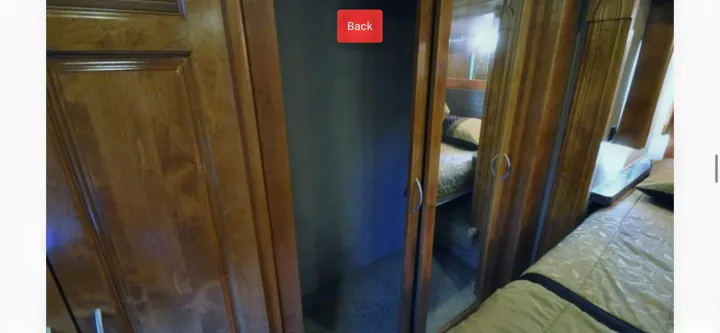RV rental interior showing a compact bedroom with wood cabinetry, open closet, and a mirrored wardrobe door reflecting the bed.. Monaco Vesta 2012