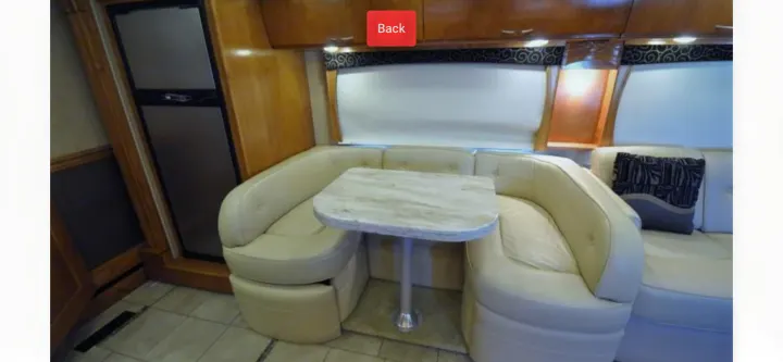 Spacious RV rental dinette featuring light seating, a stone-look table, and integrated fridge. Ideal for on-the-road dining.. Monaco Vesta 2012