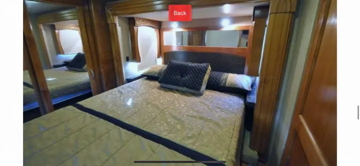 Cozy RV rental bedroom with patterned bedding, wood interior, and mirrored closet.. Monaco Vesta 2012