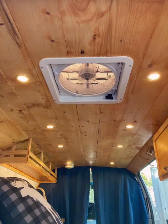 Wood-paneled ceiling with a central fan and bright LED lights inside this cozy RV rental, featuring a custom wooden bunk.. Ford Econoline 2012