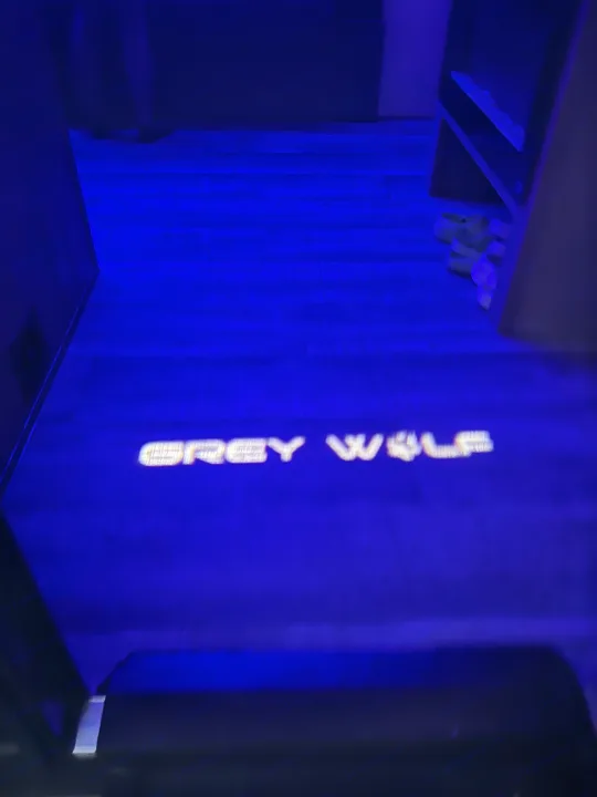 Blue-lit RV rental interior with a 'Grey Wolf' logo projected on the floor, showcasing a cozy, modern leisure vehicle.. Forest River Cherokee Grey Wolf 26DBH 2023