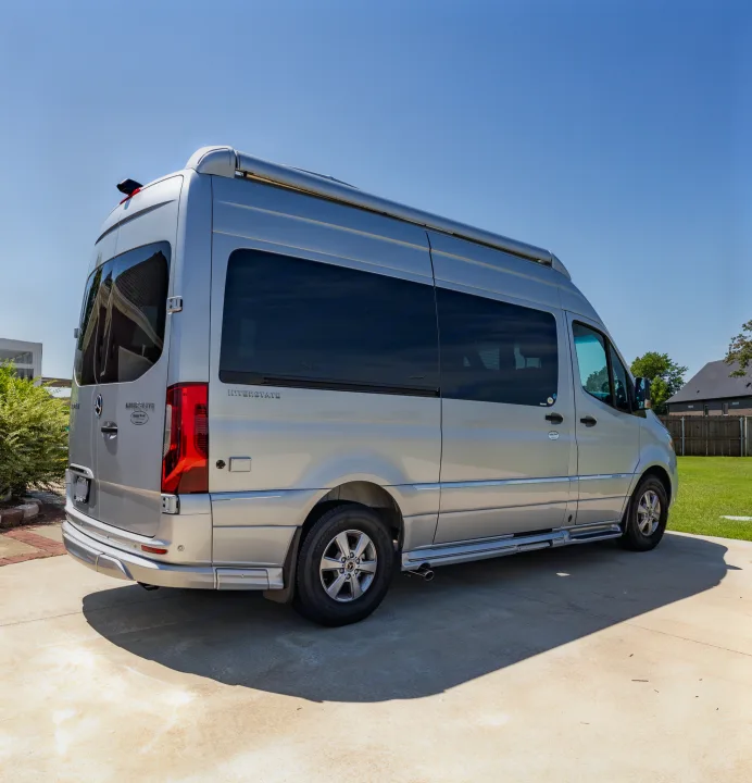 This silver Airstream Interstate RV rental, a Mercedes-Benz Sprinter conversion, is parked on a sunny day.. Airstream Interstate 2023
