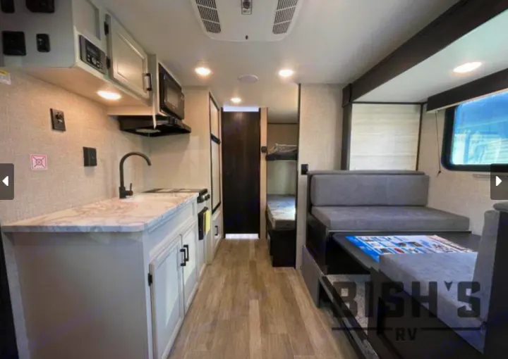 This RV rental interior shows a full kitchen, dinette, and bunk beds, offering a compact living space for road trips.. Jayco Jay Flight SLX 2023