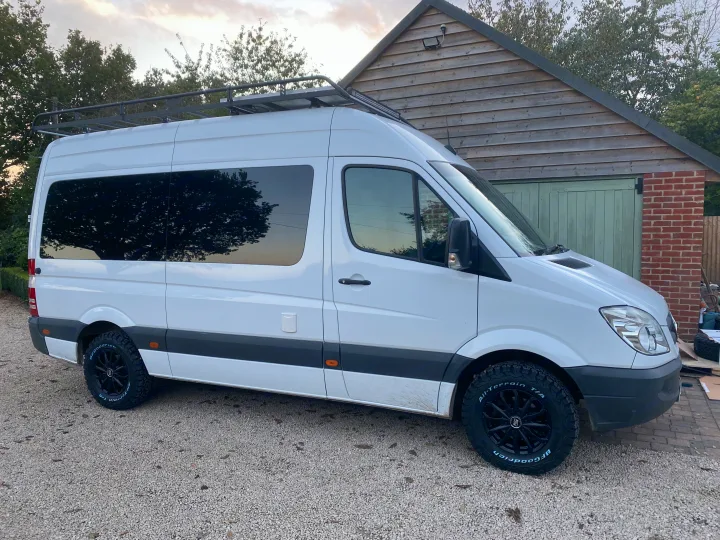 White Mercedes Sprinter van with roof rack, solar, and all-terrain tires, ready for your next RV rental adventure.. Mercedes-Benz Sprinter 2012