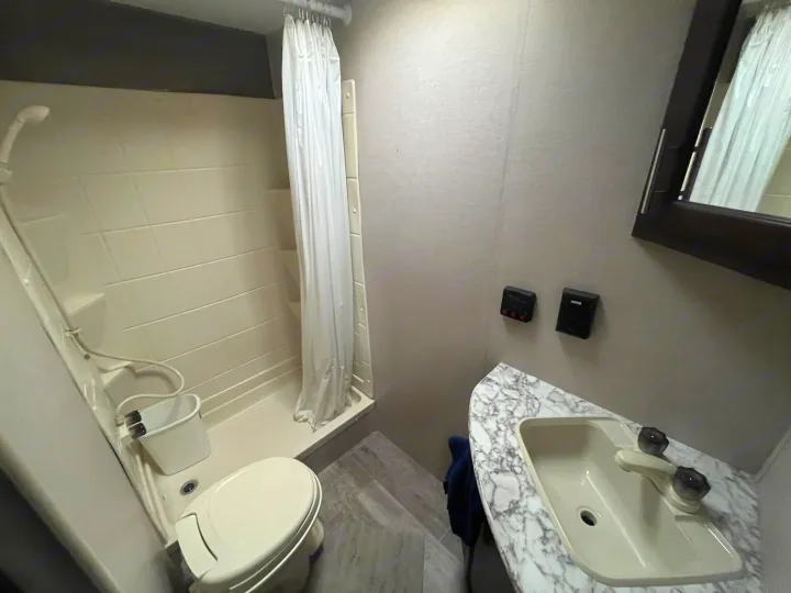 Bright RV rental bathroom with shower, toilet, and vanity sink. Compact, functional design for road trips.. Sportsmen LE 2018
