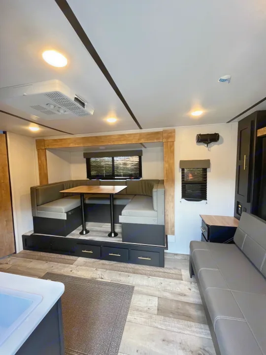 Modern RV rental interior featuring a spacious dinette, comfortable sofa, and ample storage.. Keystone RV Springdale 2023