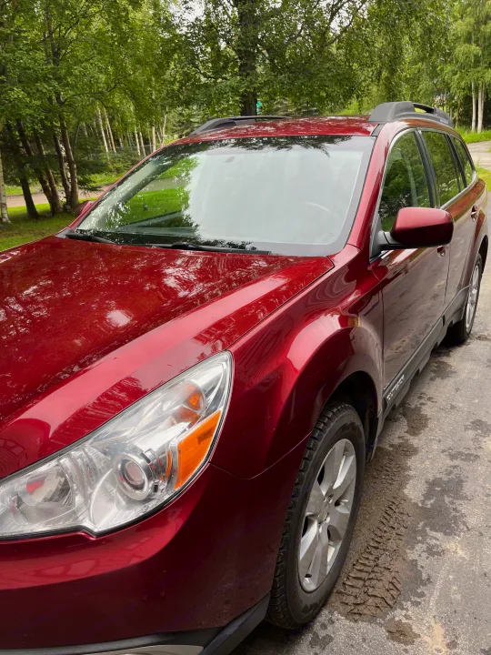 Red car on driveway. Explore travel options, including an rv rental, for your next outdoor adventure.. Subaru Outback 2012