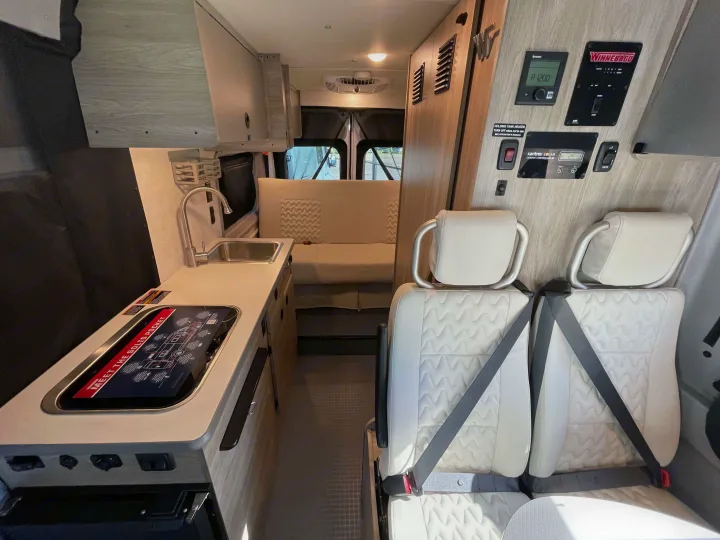 Explore this Winnebago RV rental interior: featuring a kitchenette, rear seating, and a detailed control panel.. Winnebago Solis 2022