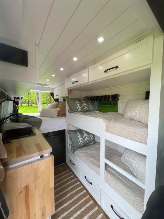 RV rental interior: cozy bunk beds, main sleeping area with outdoor view, and compact kitchen.. Mercedes-Benz Sprinter 2017