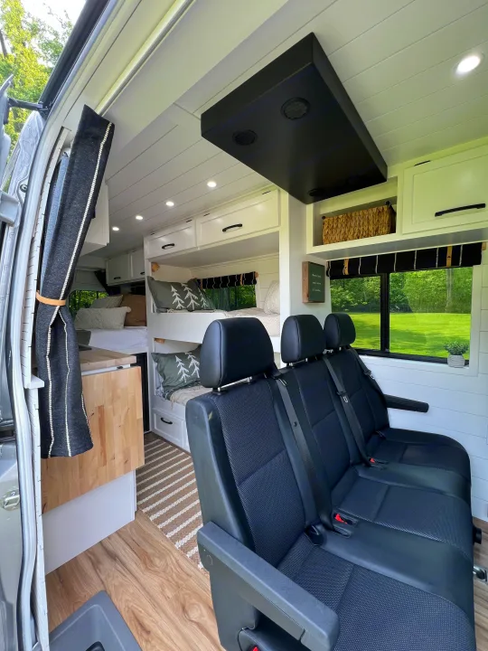 RV rental: Bright campervan interior with bunk beds, passenger seating, white shiplap walls, and wood-look flooring.. Mercedes-Benz Sprinter 2017
