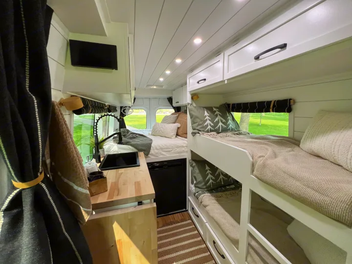 Bright RV rental interior: kitchen with sink, main bed, and bunk beds for family comfort.. Mercedes-Benz Sprinter 2017