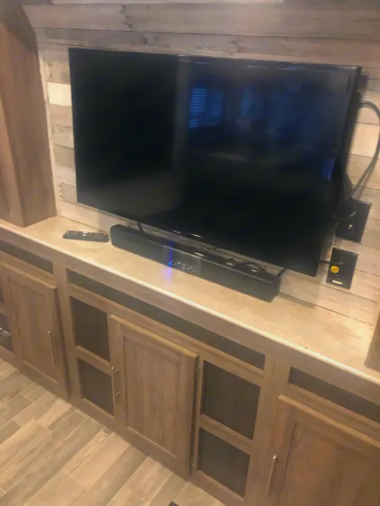 Cozy RV rental interior with TV, soundbar, remote, and light wood cabinetry for entertainment & storage.. Crossroads RV Zinger Lite 2022
