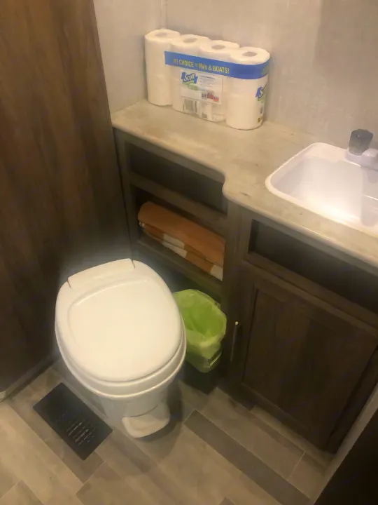Compact RV rental bathroom: features a toilet, sink, and essentials including Scott RV toilet paper, storage, and a small trash bin.. Crossroads RV Zinger Lite 2022