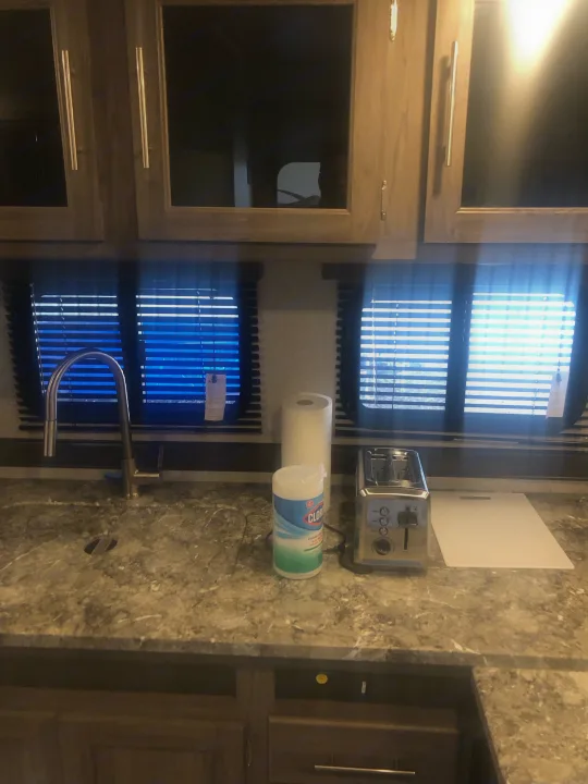 RV rental kitchen: sink, toaster, paper towels, and wipes on a marbled counter. Bright windows, overhead cabinets.. Crossroads RV Zinger Lite 2022