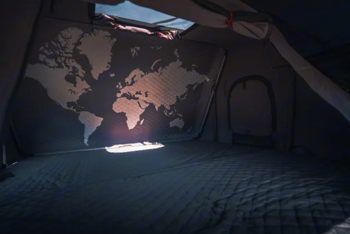 Interior of an RV rental: a quilted world map spans the back wall above a soft bed, inviting travels and camping adventures.. Toyota Tacoma 2023