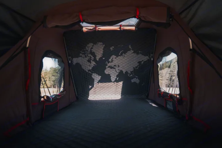 Inside a cozy **rv rental** tent: a quilted interior with a world map on the back wall and side windows showing nature.. Toyota Tacoma 2023