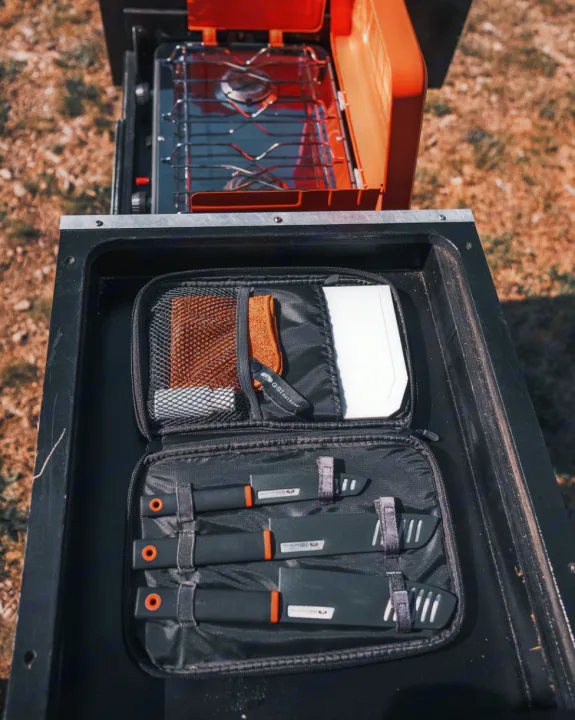 Compact camping kitchen for your RV rental: stove, knives, and cleaning tools organized for adventure.. Toyota Tacoma 2023