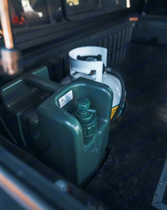 Essential gear for your RV rental adventure: a portable fuel/water container and propane tank in a vehicle cargo area.. Toyota Tacoma 2023