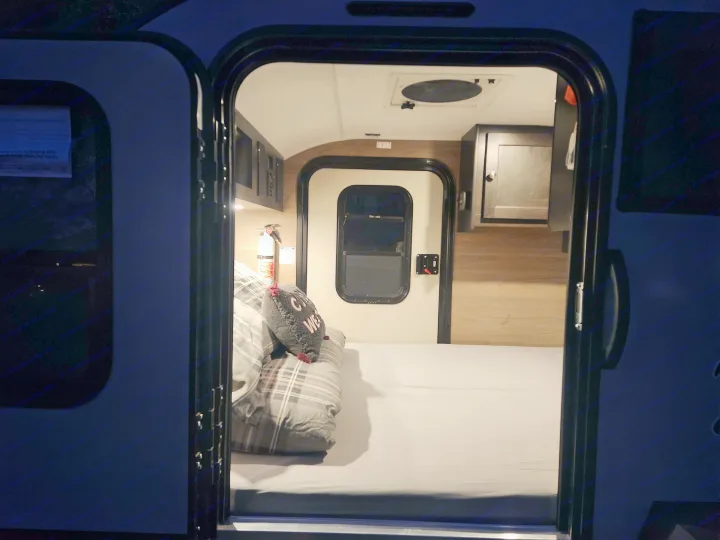 Step into this cozy RV rental: compact interior features a made bed, storage, and visible fire extinguisher for safety.. Braxton Creek Bushwacker 2023
