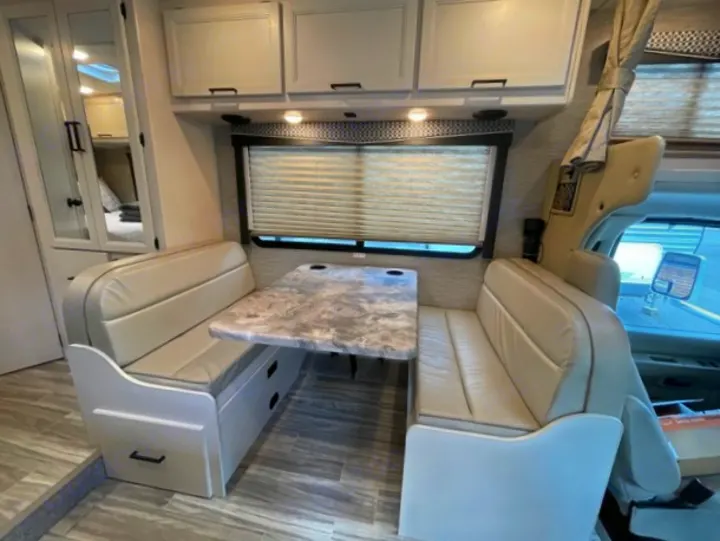 RV rental interior: A bright dinette with upholstered benches, marled table, and storage drawers for comfortable travel.. Thor Motor Coach Four Winds 2022