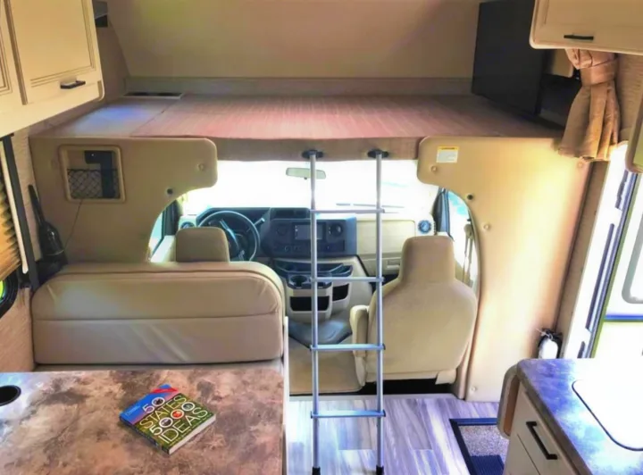 Step inside this RV rental, featuring the cockpit, a ladder leading to the large over-cab bunk, and a cozy living area.. Thor Motor Coach Four Winds 2022
