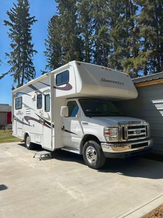 White Sunseeker Class C RV rental parked on a concrete driveway with trees. Ready for your next adventure.. Forest River Sunseeker 2010