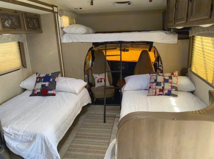 Spacious RV rental interior featuring comfortable bunk beds over the cab and two twin beds, perfect for family travel.. Chevy 4500 2019