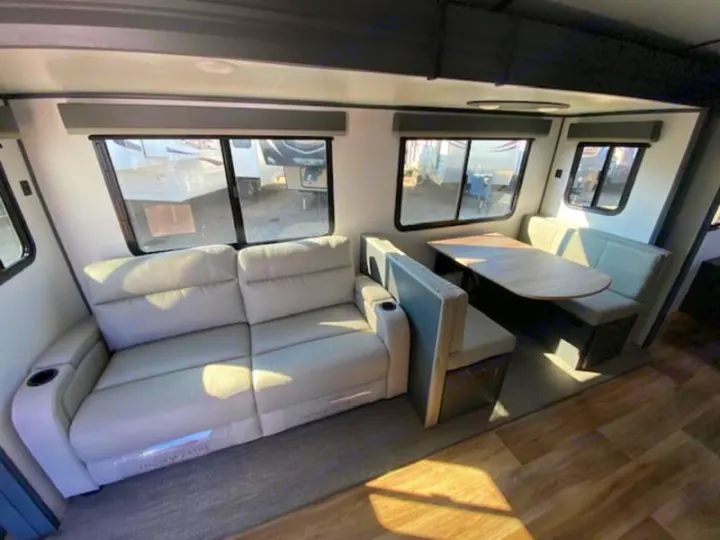 Modern RV rental interior: spacious living area with reclining sofa, dining booth, and large windows.. Keystone RV Bullet Premier Ultra Lite 2022