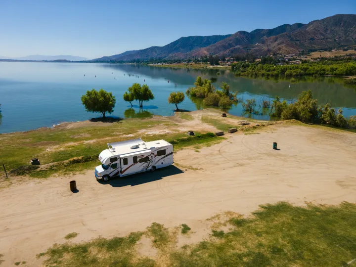 An RV rental is perfectly parked lakeside, offering stunning views of water and mountains. Ideal for your next adventure!. Thor Coleman 2023