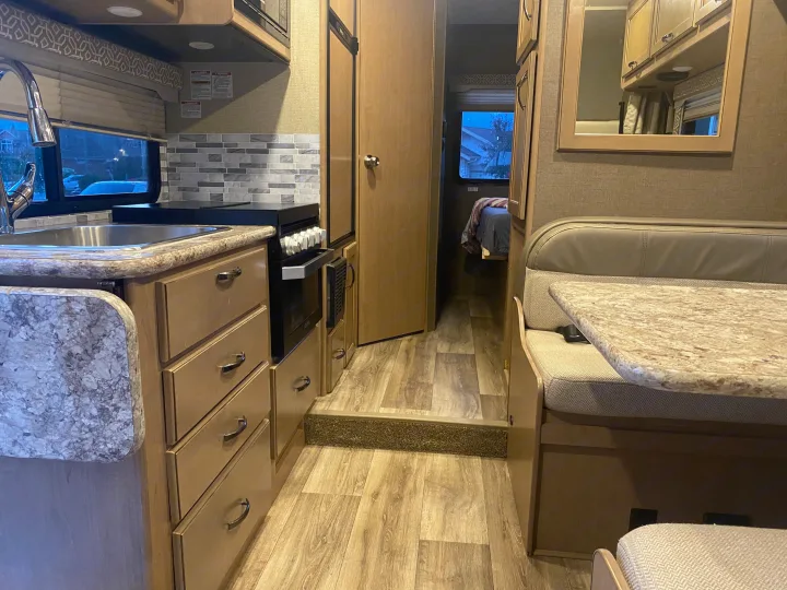 This clean, modern rv rental interior features a fully equipped kitchen, comfortable dinette, and bedroom access.. Thor Freedom Elite 2019