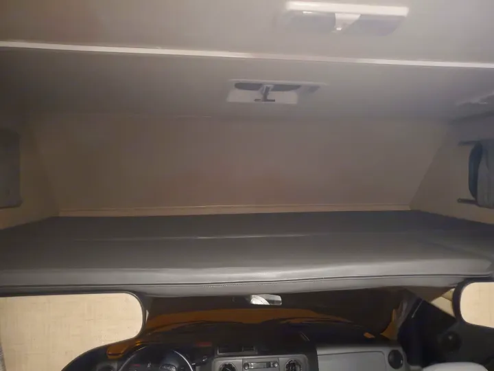 View inside an RV rental, featuring the comfortable cab-over sleeping area directly above the driver's console.. Thor Majestic 2019