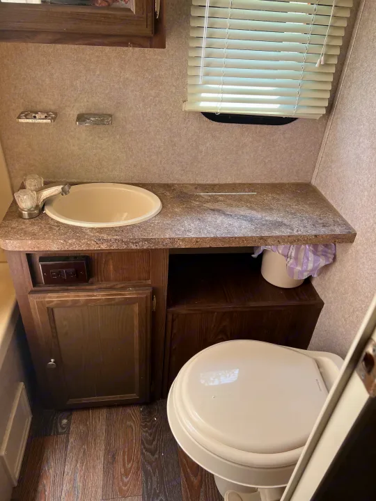 RV rental: A compact bathroom with a sink, faucet, countertop, toilet, and window with blinds.. Forest River Rockwood Mini Lite 2017