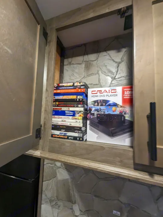 RV rental: Cabinet storage for entertainment. Stack of DVDs, new Craig HDMI DVD player, & stone-look interior walls.. Forest River Cherokee Wolf Pack Toy Hauler 2022
