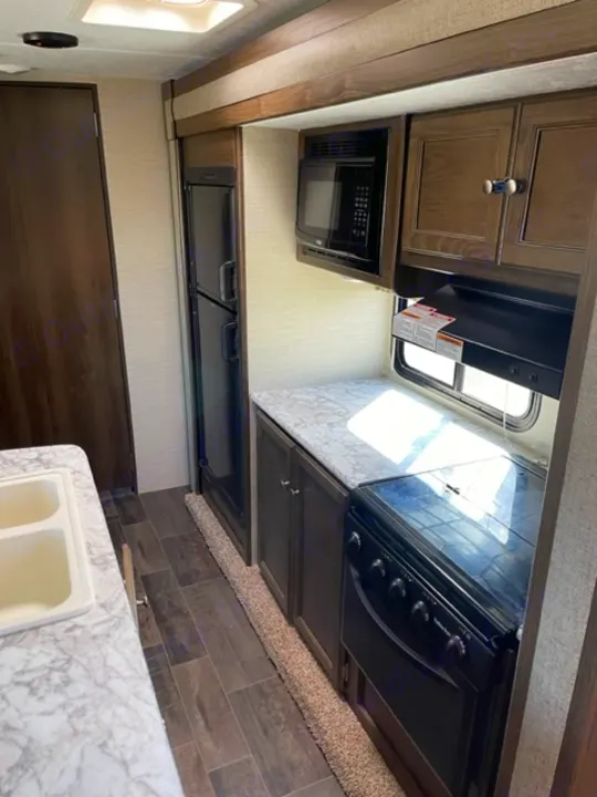 RV rental kitchen: Microwave, stove, sink, and fridge are visible in this well-equipped RV interior.. Keystone RV Bullet Ultra Lite 2018