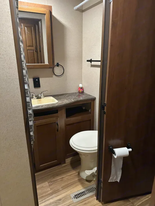 Inside this RV rental, a compact bathroom boasts a practical sink, vanity, and toilet, with a toilet paper holder on the door.. Jayco Jay Flight 2016