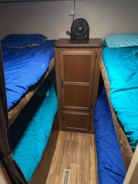 RV rental bunk beds: two sets with blue bedding, a central cabinet with a fan, and wood floors. A compact sleeping area.. Jayco Jay Flight 2016