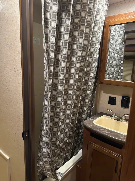 RV rental bathroom: Shower with geometric curtain, vanity, sink, and mirror. Space-saving design.. Jayco Jay Flight 2016