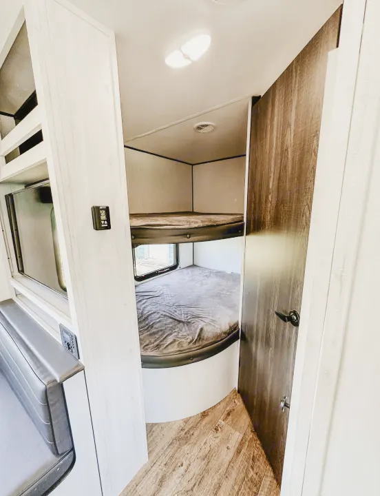 Cozy RV rental bunk beds, perfect for family adventures. Features include a thermostat, window, and overhead light.. Heartland RVs Trail Runner 2022