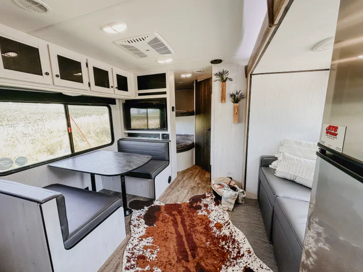 Cozy RV rental interior with dinette, TV, sofa, and bunk beds, offering a comfortable and well-appointed travel space.. Heartland RVs Trail Runner 2022