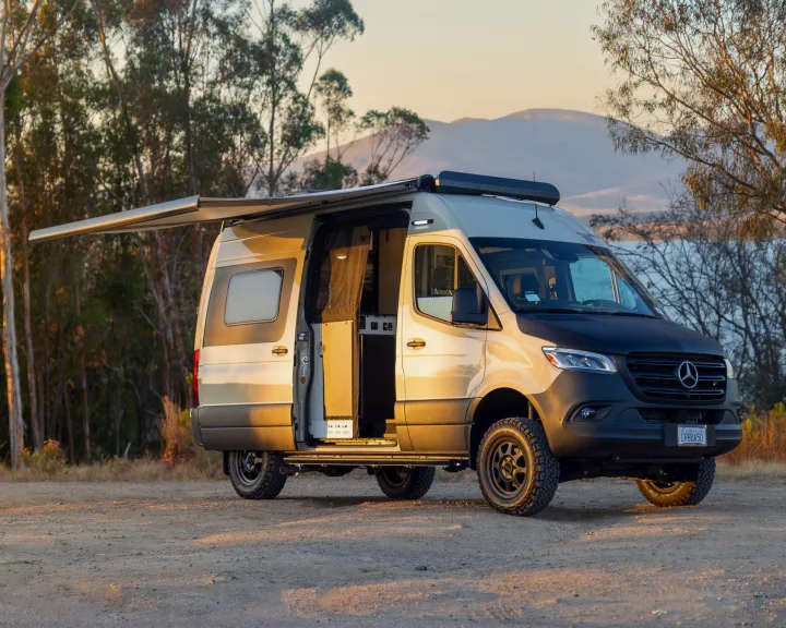 Spacious Mercedes-Benz Sprinter camper van rv rental with awning extended, parked outdoors by a lake.. Winnebago Revel 2023