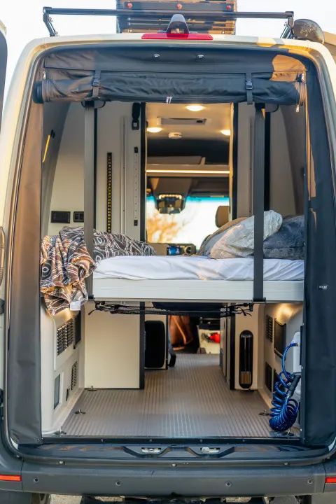 Inside a versatile RV rental camper van with an elevated bed, ample storage, and utility access. Ready for adventure!. Winnebago Revel 2023