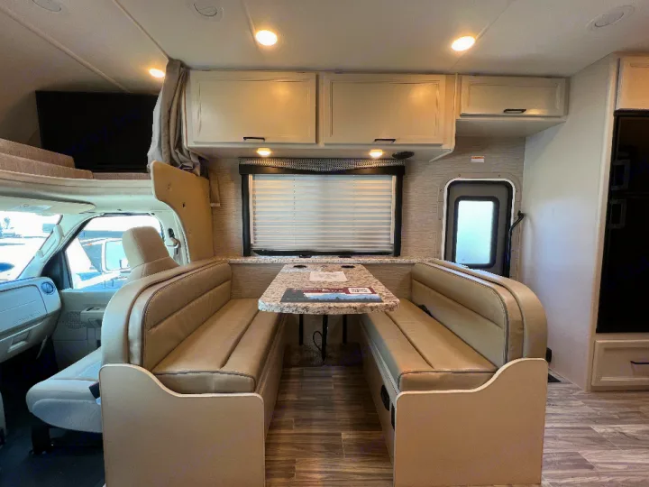 Spacious RV rental interior with comfortable dinette, kitchen cabinets, overhead bunk, and TV. Perfect for road trips.. Thor Freedom Elite 2023