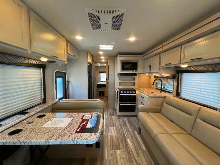 Spacious rv rental interior featuring a bright kitchen, dining dinette, and comfortable sofa.. Thor Freedom Elite 2023