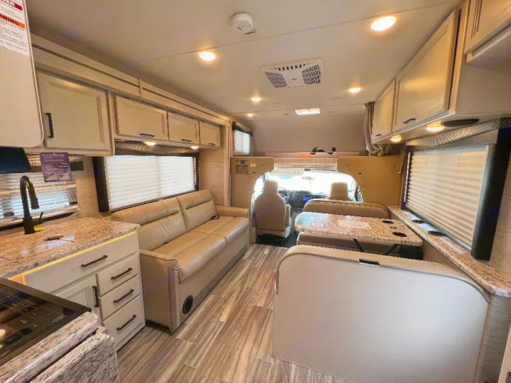 Inside a modern RV rental: a spacious living area with kitchen, sofa, and dinette, perfect for comfortable travel adventures.. Thor Freedom Elite 2023