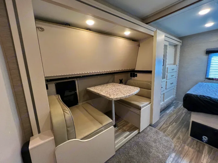 RV rental: Bright interior featuring a compact dinette with a fold-down bunk above, plus a cozy bedroom area.. Thor Freedom Elite 2023