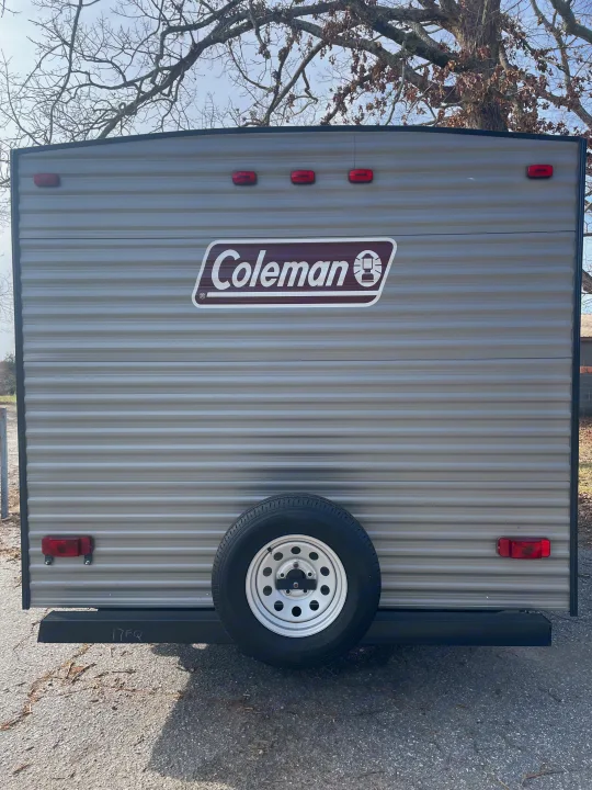Rear view of a gray Coleman travel trailer, featuring a spare tire and red lights. Ideal for an RV rental.. Dutchmen Coleman Lantern LT 2019